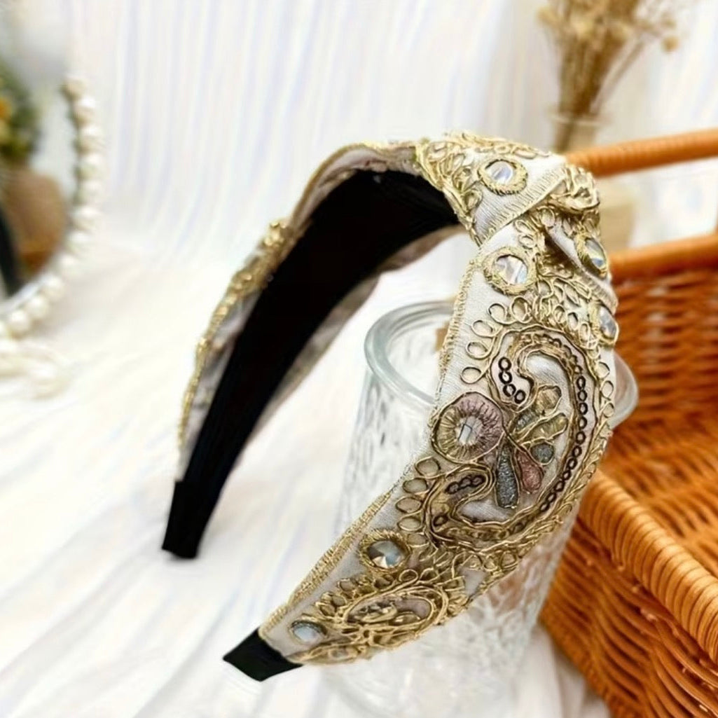Decorative gold headband on a glass surface with a blurred background
