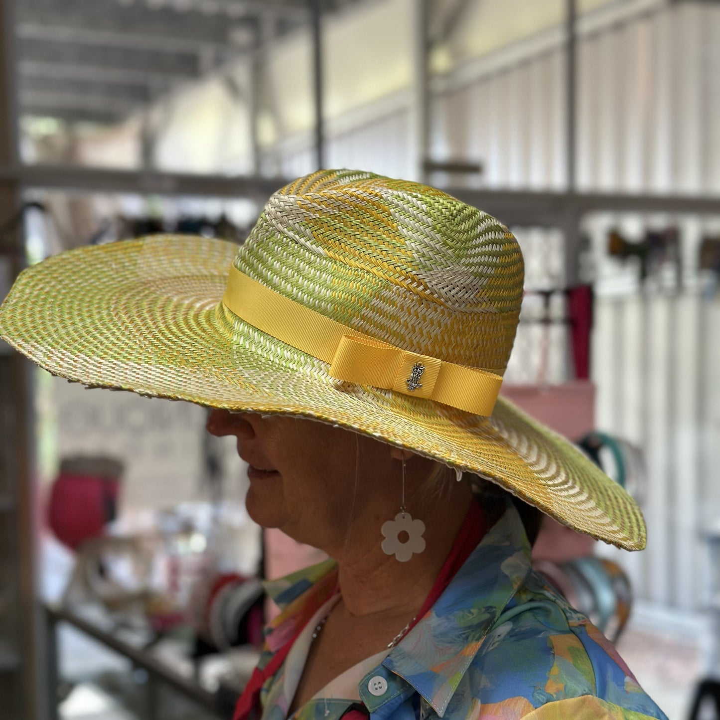 Person wearing a yellow straw hat with a bow, standing indoors.