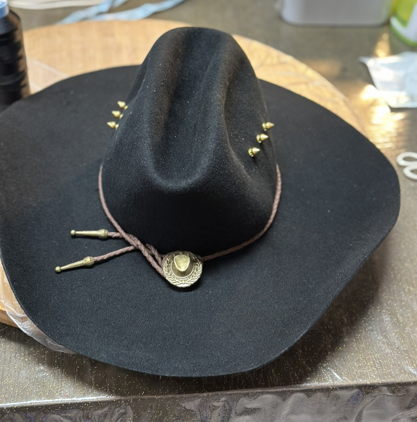 Black cowboy hat with gold accents on a metallic surface