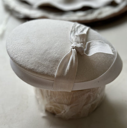 Round white button base with a ribbon on a light surface