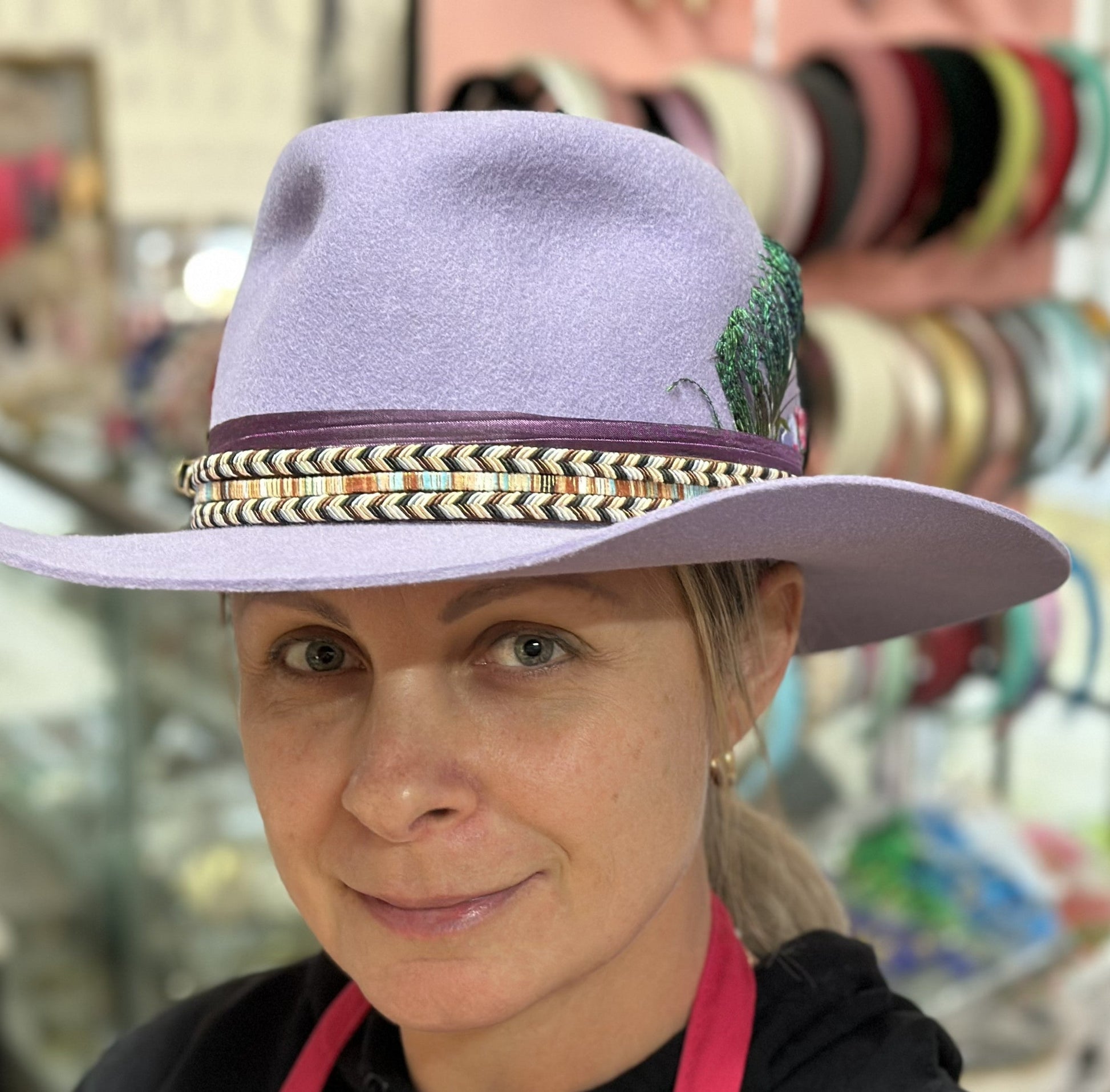 Woman wearing a purple hat with decorative band in front of a colorful background