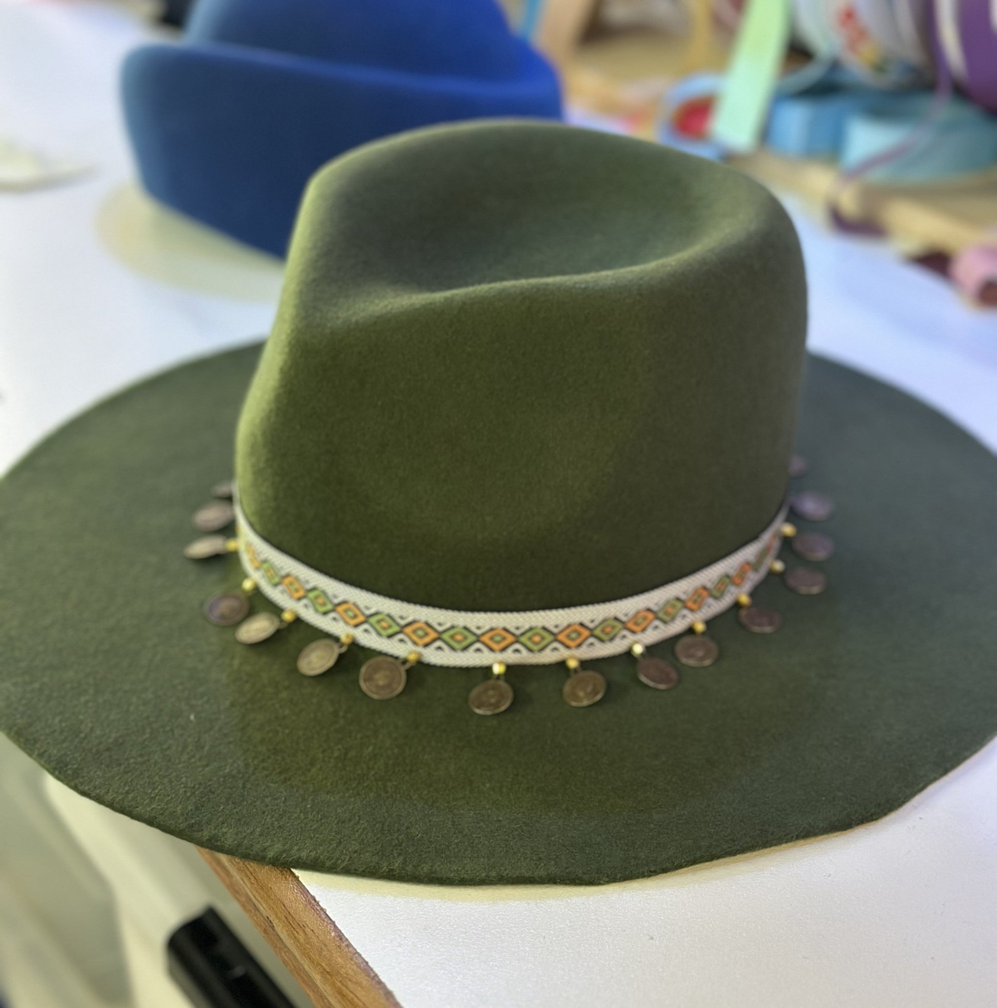 Green hat with decorative band and coins on a blurred background