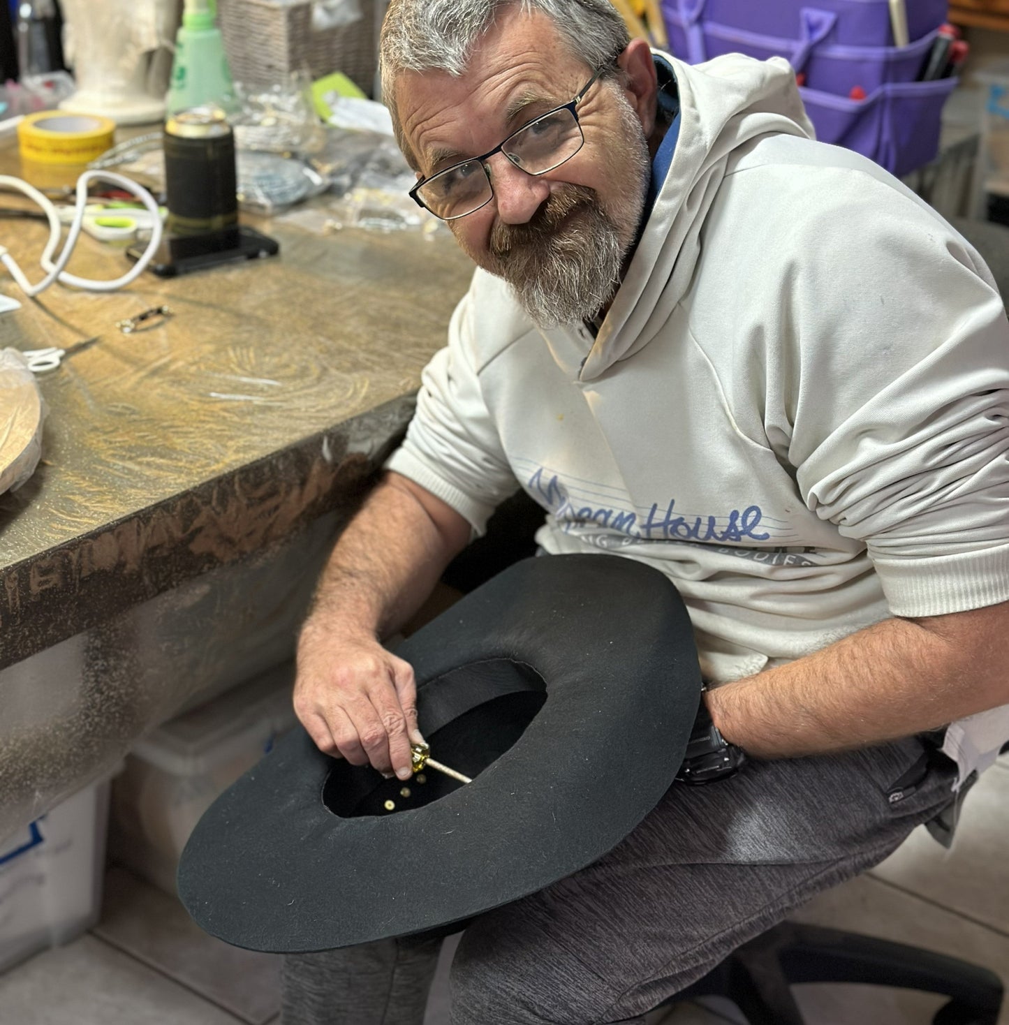 Man working on a cowboy hat in a workshop setting