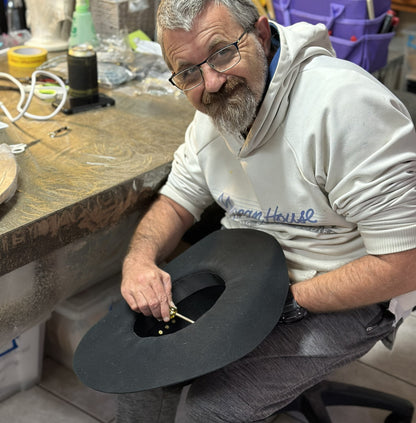 Man working on a cowboy hat in a workshop setting